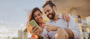 Usměvavá slečna si dává občerstvení a kouká do svého mobilu.