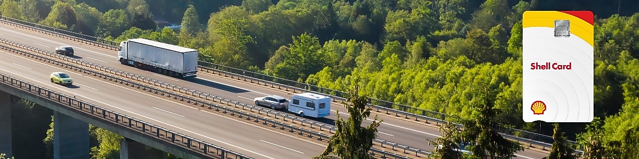 Камион се движи по криволичещ път в зелени полета. От дясната страна е изобразена карта Shell.