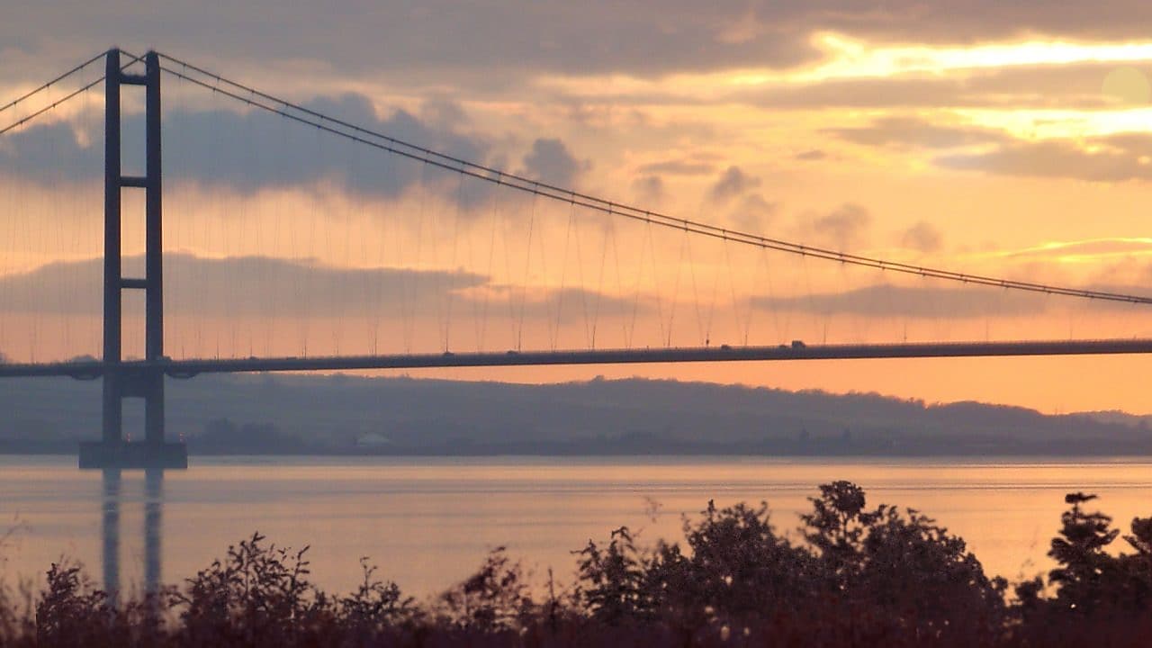 окачен мост над река при залез
