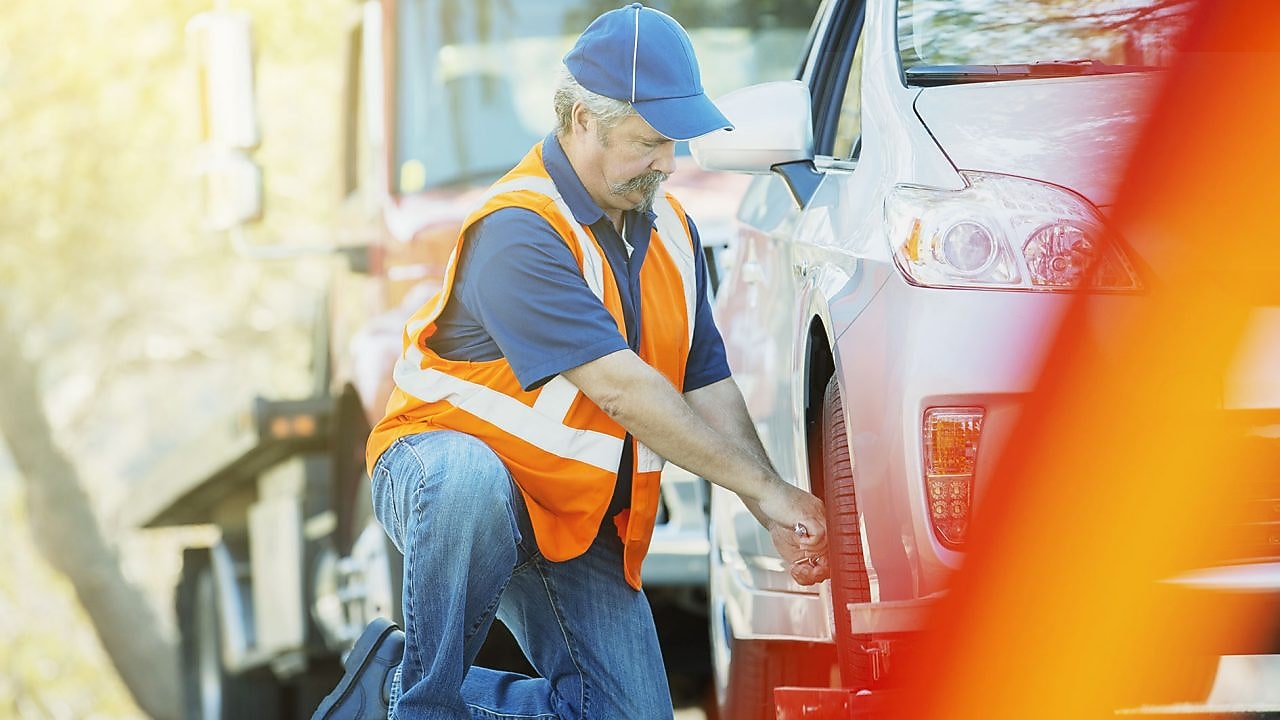 човек, който сменя автомобилна гума