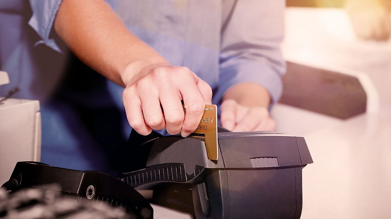 лице, което прекарва кредитна карта през устройство