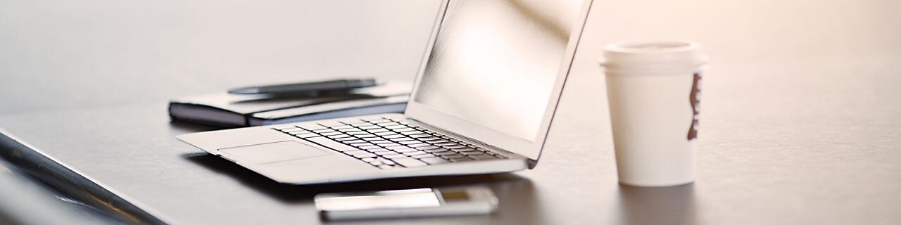 лаптоп, мобилен телефон и кафе върху бюро