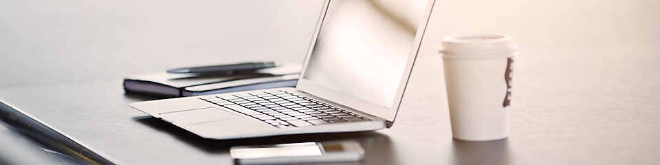лаптоп, мобилен телефон и кафе върху бюро